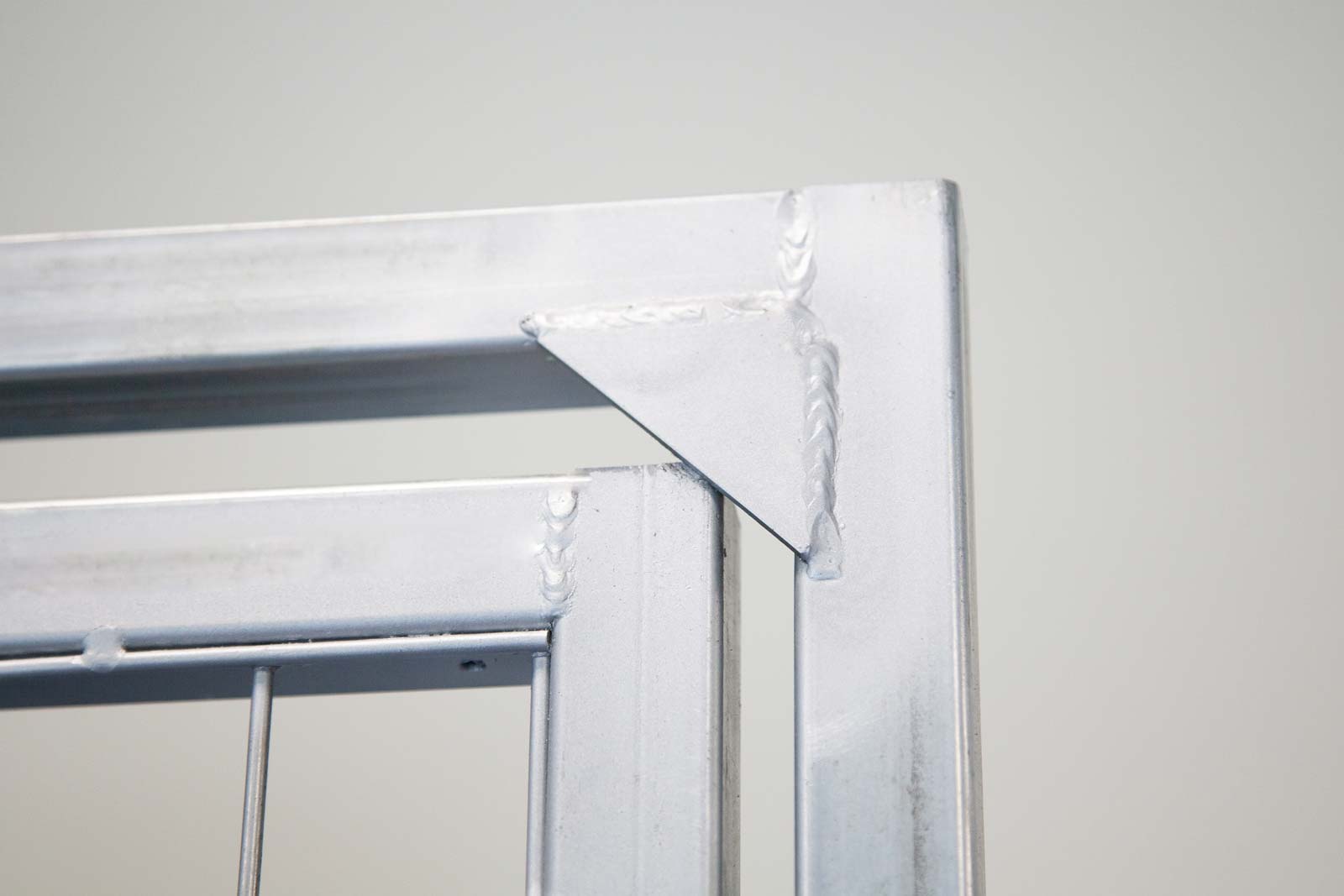 particolare di un fermaporta in acciaio saldato sul telaio che impedisce l'apertura del cancello verso l'esterno